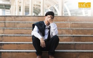 stressed man covering his face sitting on stairs