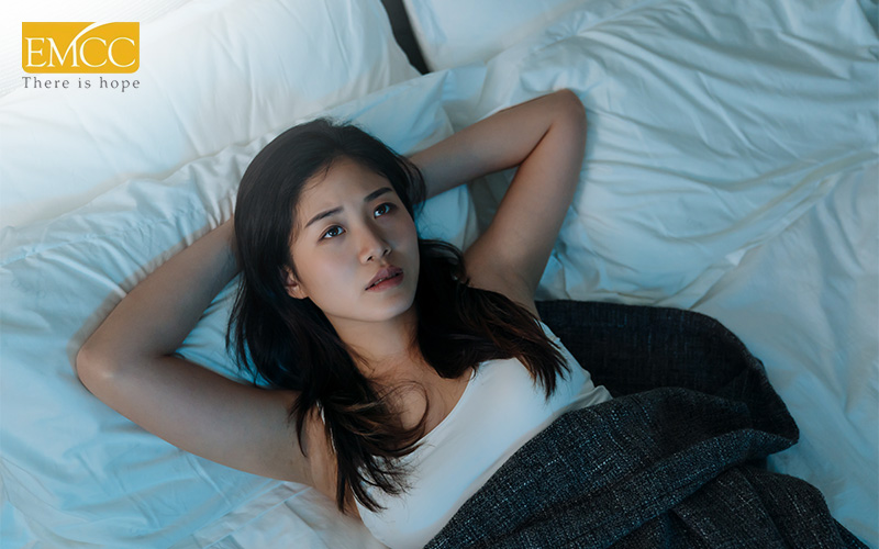 Woman awake in bed, showing insomnia caused by physical stress.