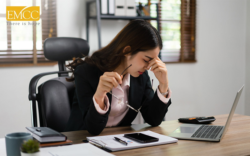 Stressed businesswoman at desk showing signs of burnout.
