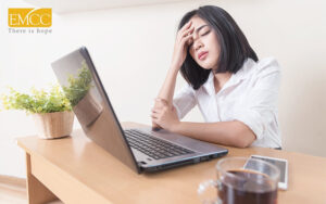 Woman experiencing stress or burnout working at laptop.