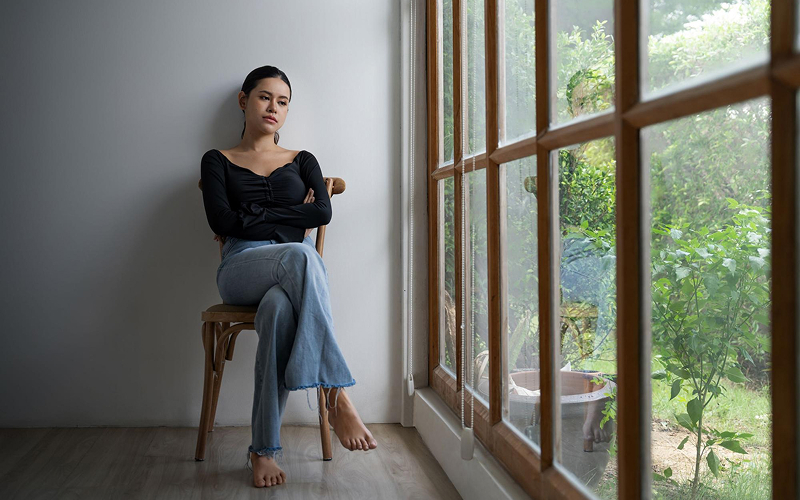 Woman sitting alone in grief avoidance after processing a loss.