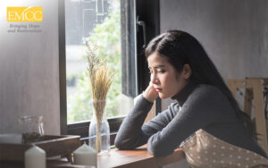 Person sitting by window in quiet reflection.