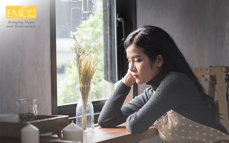 Person sitting by window in quiet reflection.
